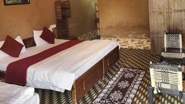 A room with a bed, a chair, a wall-mounted air conditioner, and a ceiling fan. - Altara Resort (Jaipur)