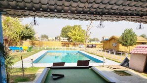 A pool area with a green deck, two lounge chairs, and a small pool. - Altara Resort (Jaipur)