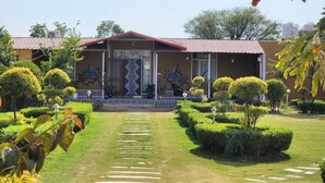 A building with a red roof and a mural on the wall. There is a pathway leading to the entrance. - Altara Resort (Jaipur)