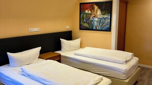 A hotel room with two beds, a painting on the wall, and a wooden wardrobe. - Your haven of peace near Hamburg Airport (Quickborn)