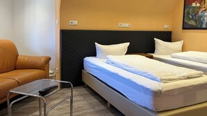 A hotel room with a bed, a chair, a small table, and a painting on the wall. - Your haven of peace near Hamburg Airport (Quickborn)