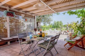 An outdoor patio with a table set for dining, cushioned seating, and potted plants. - Gorgeous and Peaceful Villa in Puglia (Monopoli)