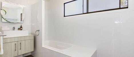 Ein modernes Badezimmer mit Waschbecken, Spiegel und Badewanne.