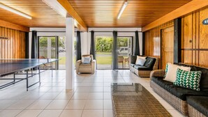 A spacious indoor area with a ping pong table, a sofa, and a wicker ottoman. - A Lure - 100m to Main Beach! (Agnes Water)