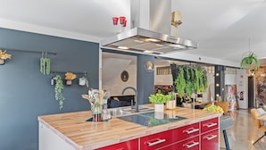 Una cocina moderna con una isla central, armarios rojos y diversas plantas.