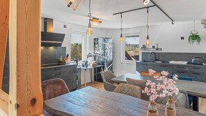 Una cocina moderna con comedor, que cuenta con iluminación colgante, un ventanal y vistas al exterior.