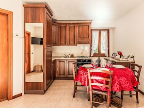 A kitchen with wooden cabinets, a dining table with red tablecloths, and a stove.