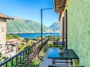 A balcony with a view of a lake and mountains, a table with a plant, and a stone wall. - Lovely apartment for 4 people with WIFI, TV and balcony (San Siro)