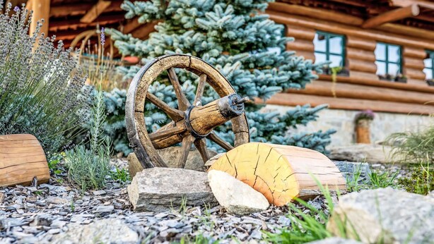A rustic outdoor setting with a wooden wheel, logs, and a wooden house in the background. - Stunning private villa for 12 guests with WIFI and patio (Dluhoště)