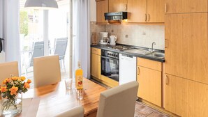 Una cocina moderna con armarios de madera, un microondas negro y un lavamanos de acero inoxidable.