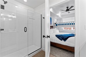 A modern bedroom with a glass shower door, a bed with a blue blanket, and a ceiling fan. - Zion Cliffside Retreat l Gem for Relaxation (Hurricane)