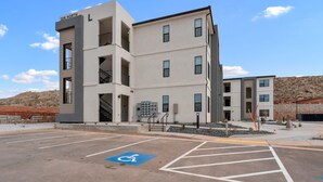 Un immeuble à plusieurs étages avec un parking situé à l’avant, comprenant une place de stationnement réservée aux personnes handicapées.