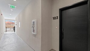 Un couloir avec une porte portant le numéro « 103 », un panneau indiquant la sortie, et une vue sur un paysage désertique.