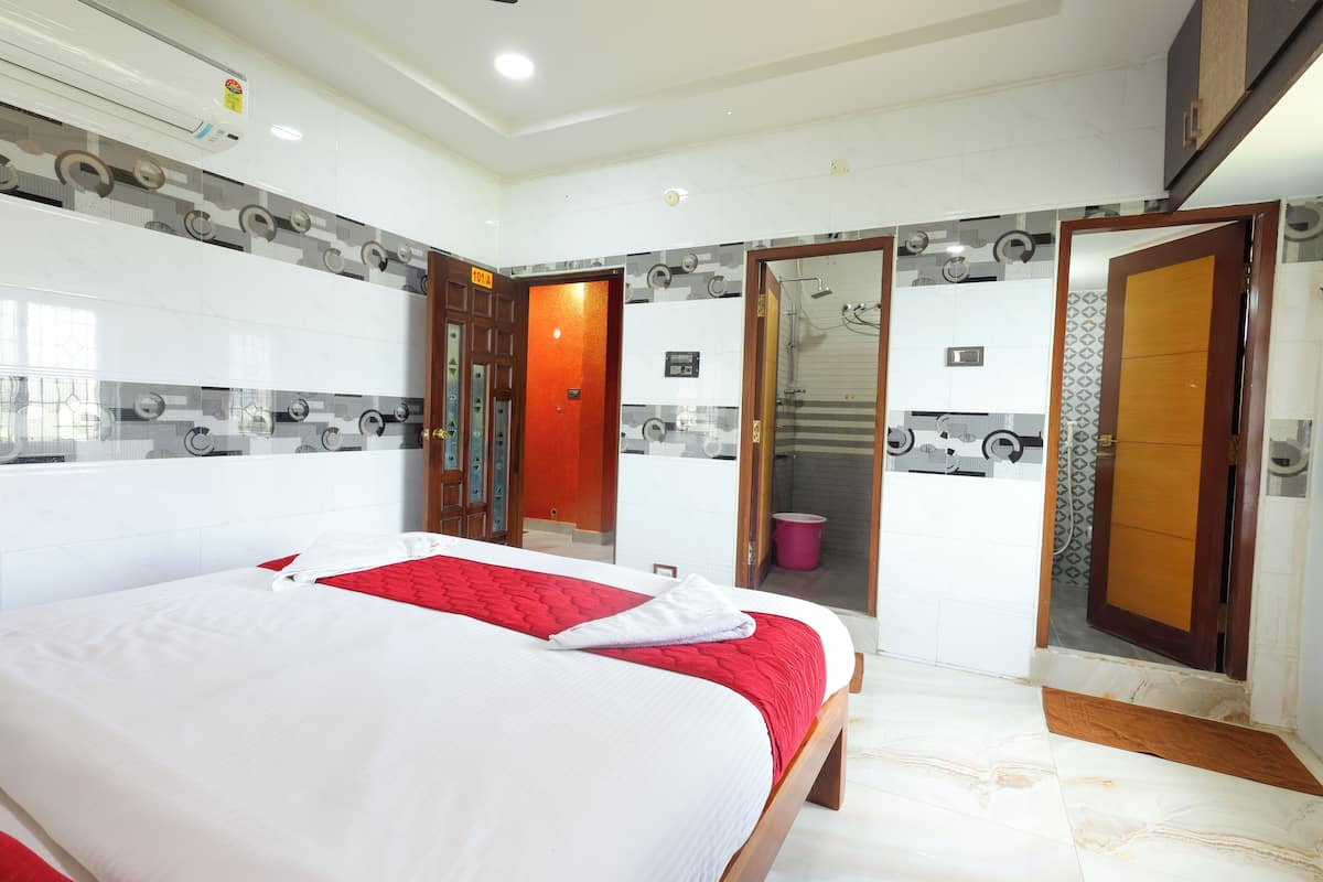 A hotel room with a large bed, a bathroom with a shower, and a door leading to another room.