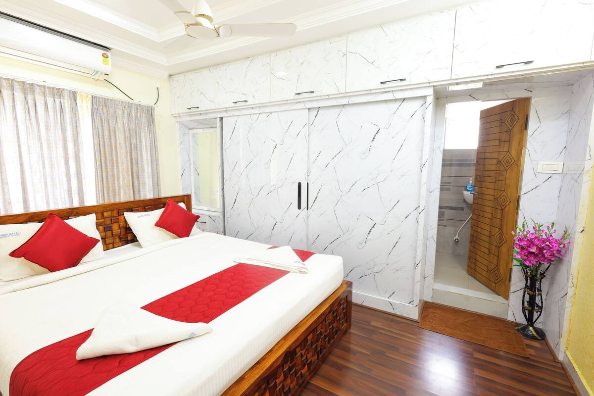 A hotel room with a large bed, a wardrobe, and a bathroom visible through an open door.