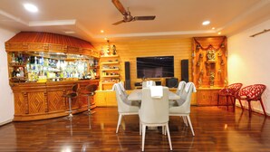 Eine Bar mit Regalen voller Spirituosenflaschen, einem Fernseher und einem Esstisch mit Stühlen.