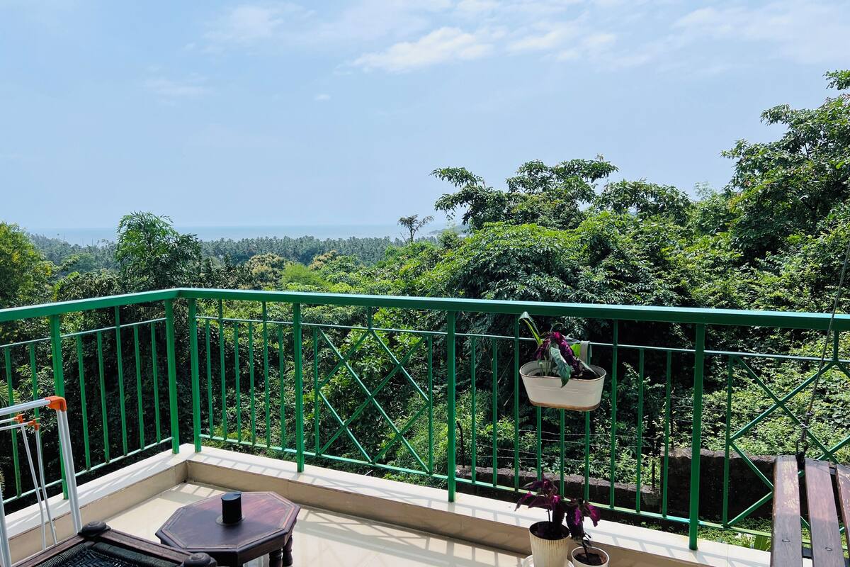 A balcony with a green railing, a small table, and potted plants.