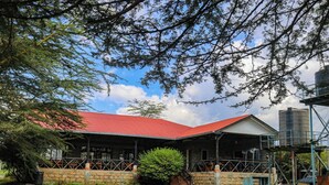 A building with a red roof, surrounded by a stone wall and a grassy area. - MT LONGONOT COUNTRY RESORT NAIVASHA (Naivasha)