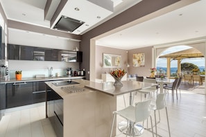 Cozinha moderna com uma ilha grande, banquetas e área de refeições com vista.