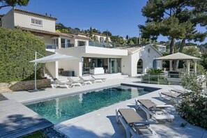 Uma casa moderna com piscina, área de estar externa e varanda coberta.