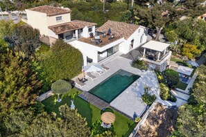 Uma casa moderna com uma piscina grande, um alpendre coberto e um jardim bem cuidado.