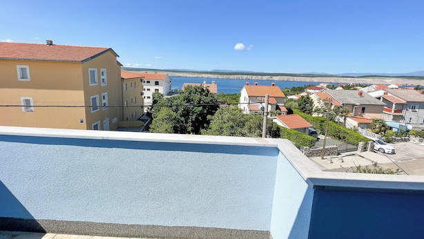 Ein Wohngebiet mit Gebäuden, blauem Himmel und Blick aufs Meer.