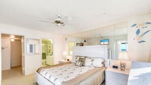Ein Schlafzimmer mit Bett, Nachttischen, einem Spiegel und einem Deckenventilator.