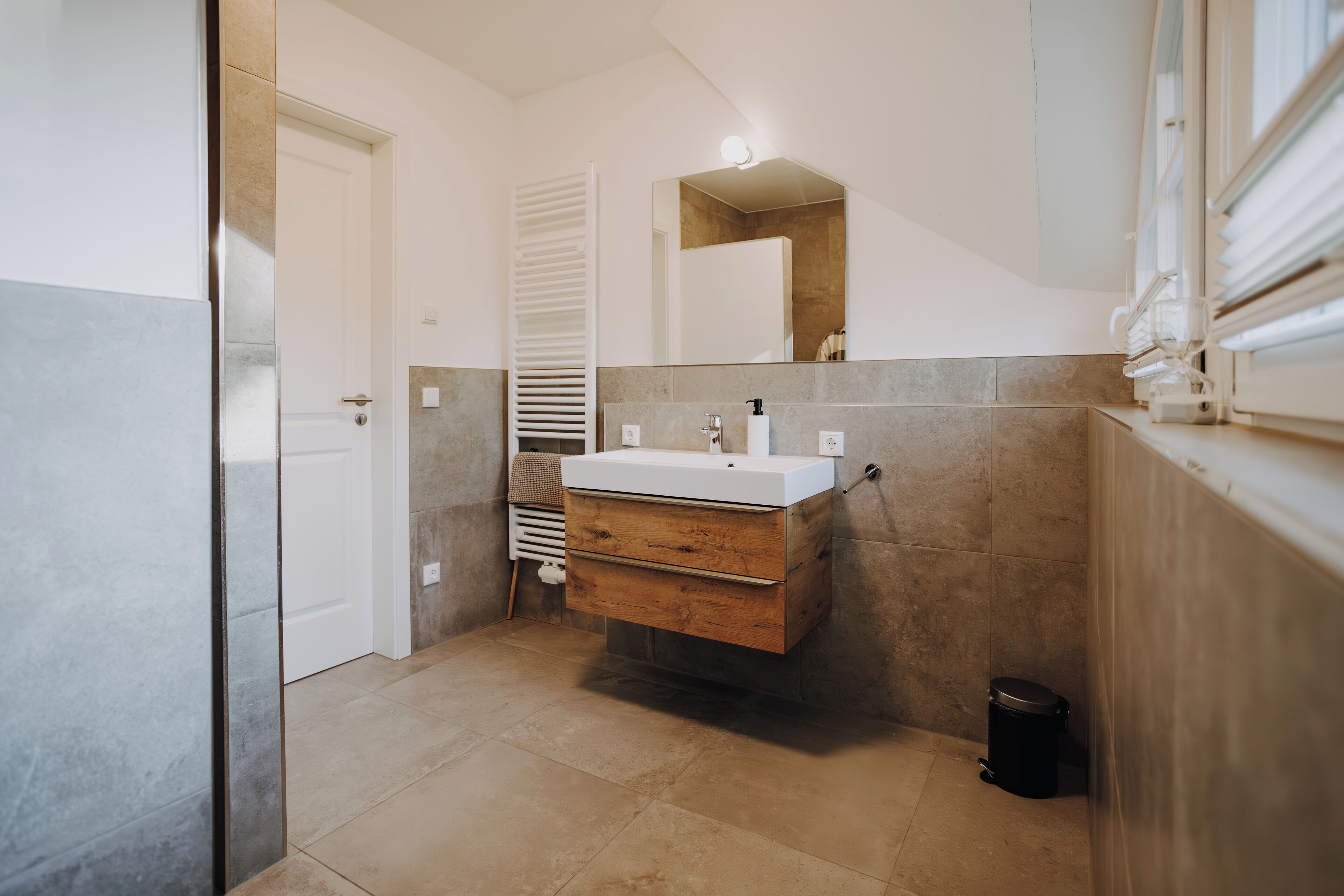 Une salle de bain moderne avec un meuble-lavabo en bois, un lavabo blanc et un miroir.