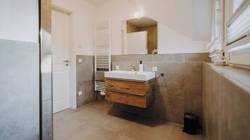Une salle de bain moderne avec un meuble-lavabo en bois, un lavabo blanc et un miroir.