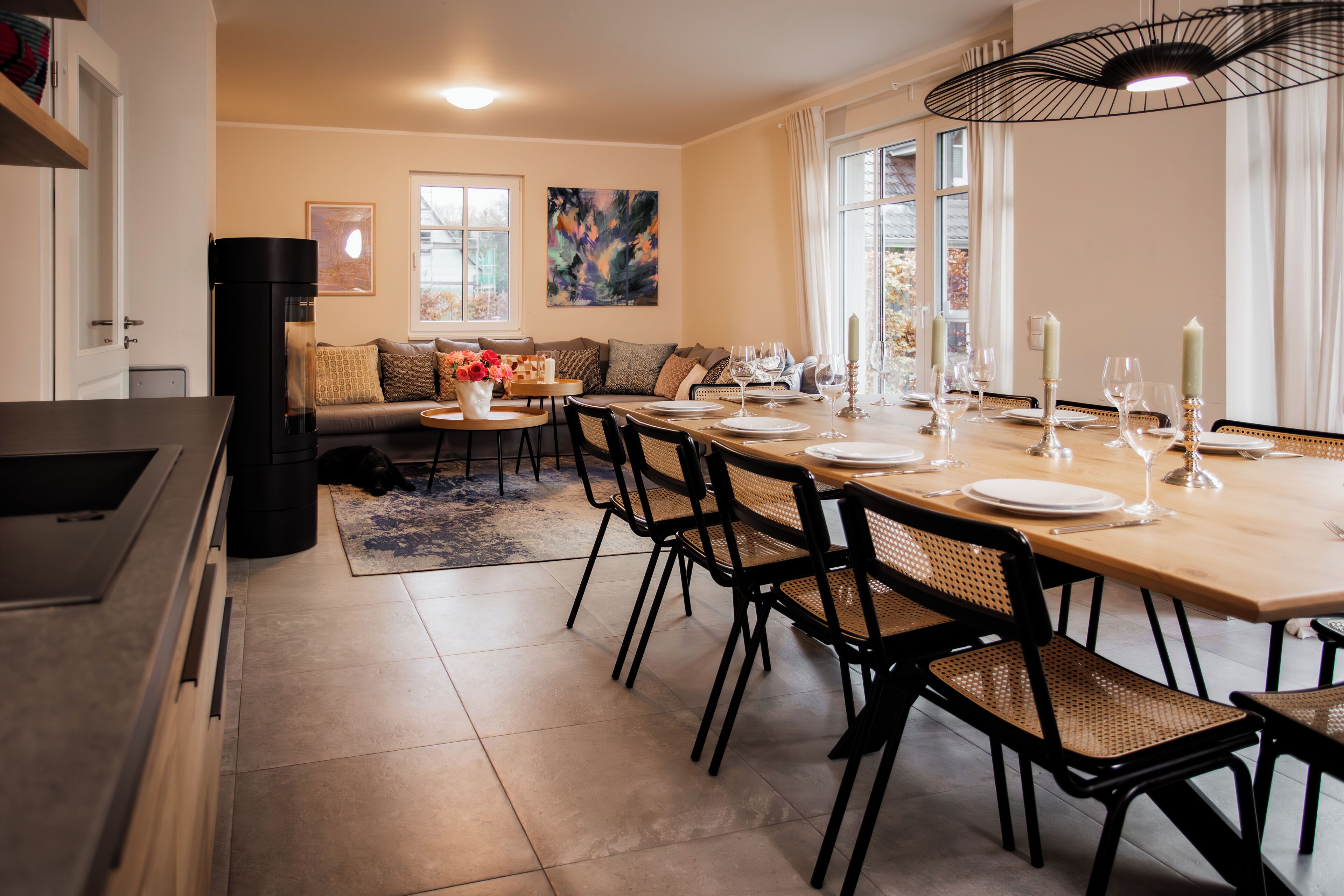 A dining area with a wooden table set for six, black chairs, and a black chandelier.