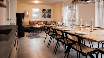 A dining area with a wooden table set for six, black chairs, and a black chandelier.