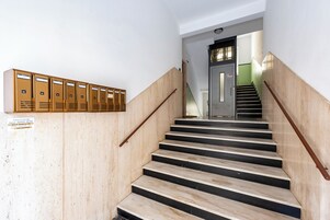 Una escalera con peldaños de madera y barandillas de metal, que conduce a una puerta con un letrero encima.