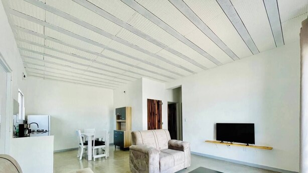 A spacious living room with a sofa, a coffee table, and a TV mounted on the wall. - Casa Les Deux R da Lagoa (Jijoca de Jericoacoara)