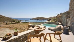Une terrasse avec une piscine, des murs en pierre et une vue sur la mer.
