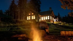 A log cabin with a fire pit in front, surrounded by trees and a starry night sky. - ADA Cabin, Queen Bed, Double Bed, Private Bath (Greenville)
