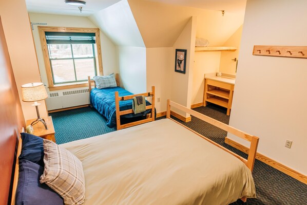 Une chambre avec un grand lit, un plus petit lit, un bureau et une fenêtre.