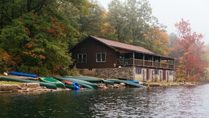 Una cabaña junto a un lago con canoas alineadas en el muelle.