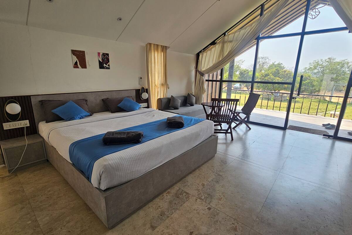 Quarto de hotel com uma cama grande, um sofá, uma cadeira e uma varanda com vista.