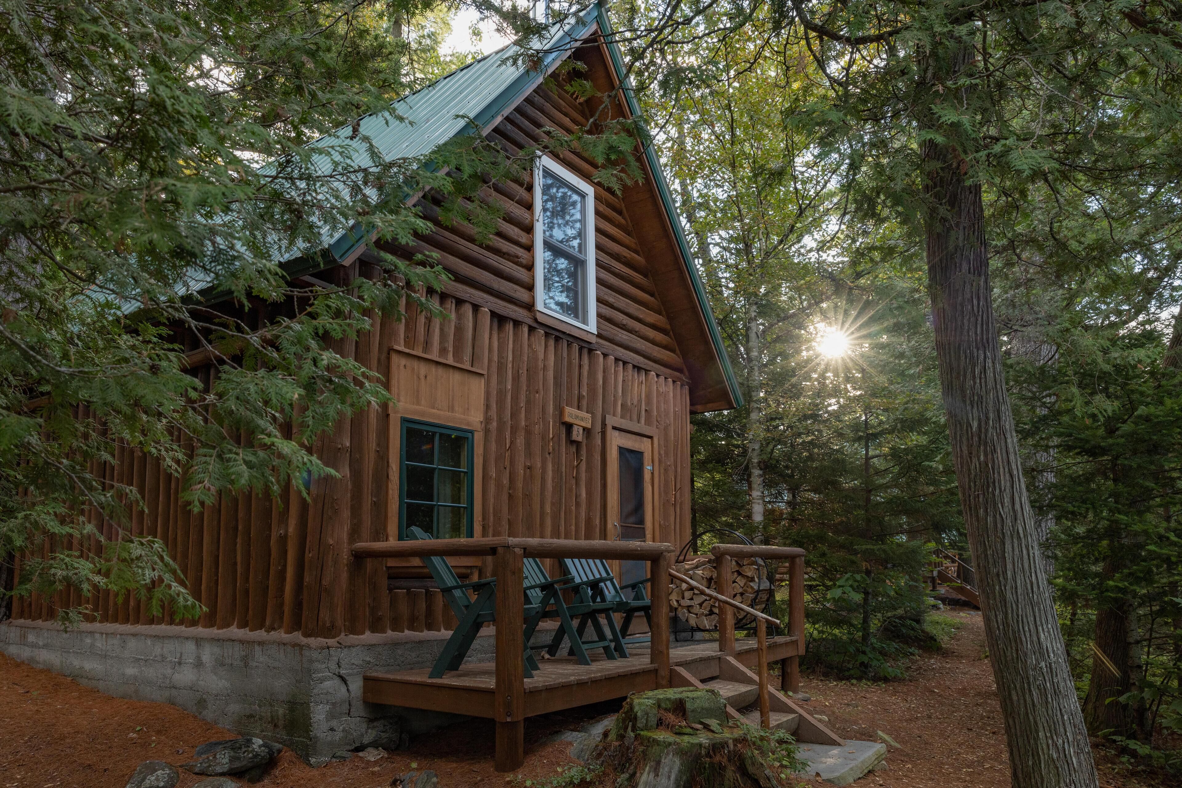 A rustic cabin with a wooden exterior, a porch with chairs, and a signboard.