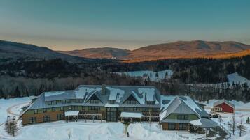 Un gran lodge con varias construcciones, un paseo techado y vistas a montañas nevadas.