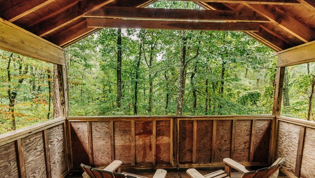 A wooden deck with two wooden chairs and a table, overlooking a dense forest. - Cabin, Double Bed, 2 Bunks, Shared Bathroom (Blairstown)
