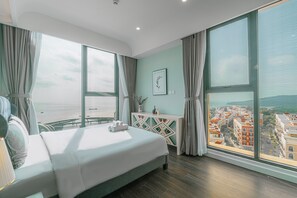 Una habitación de hotel moderna con una cama grande, vistas a la ciudad y un balcón.