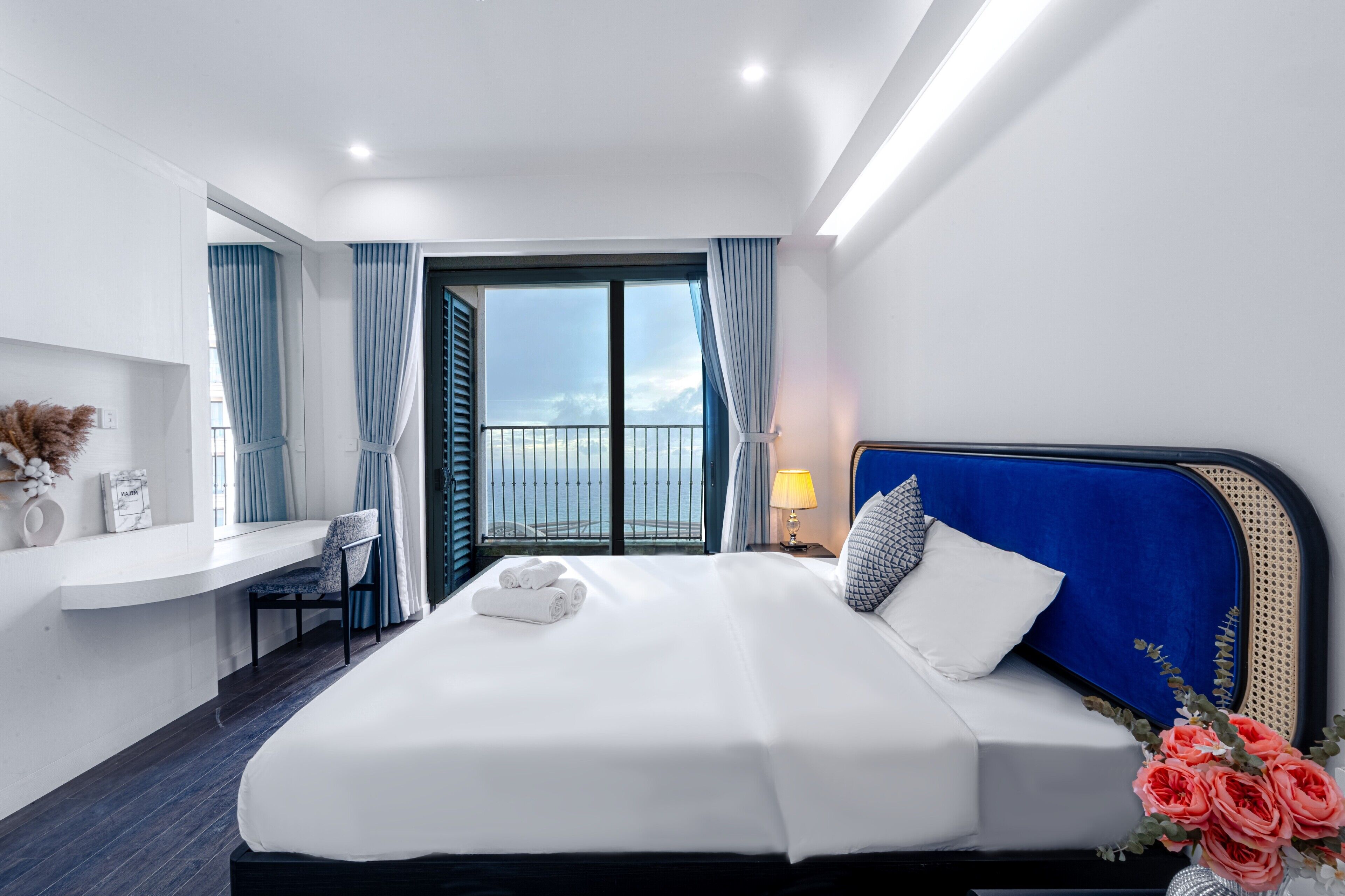 Habitación de hotel moderna con una cama grande, un escritorio y vista al mar.