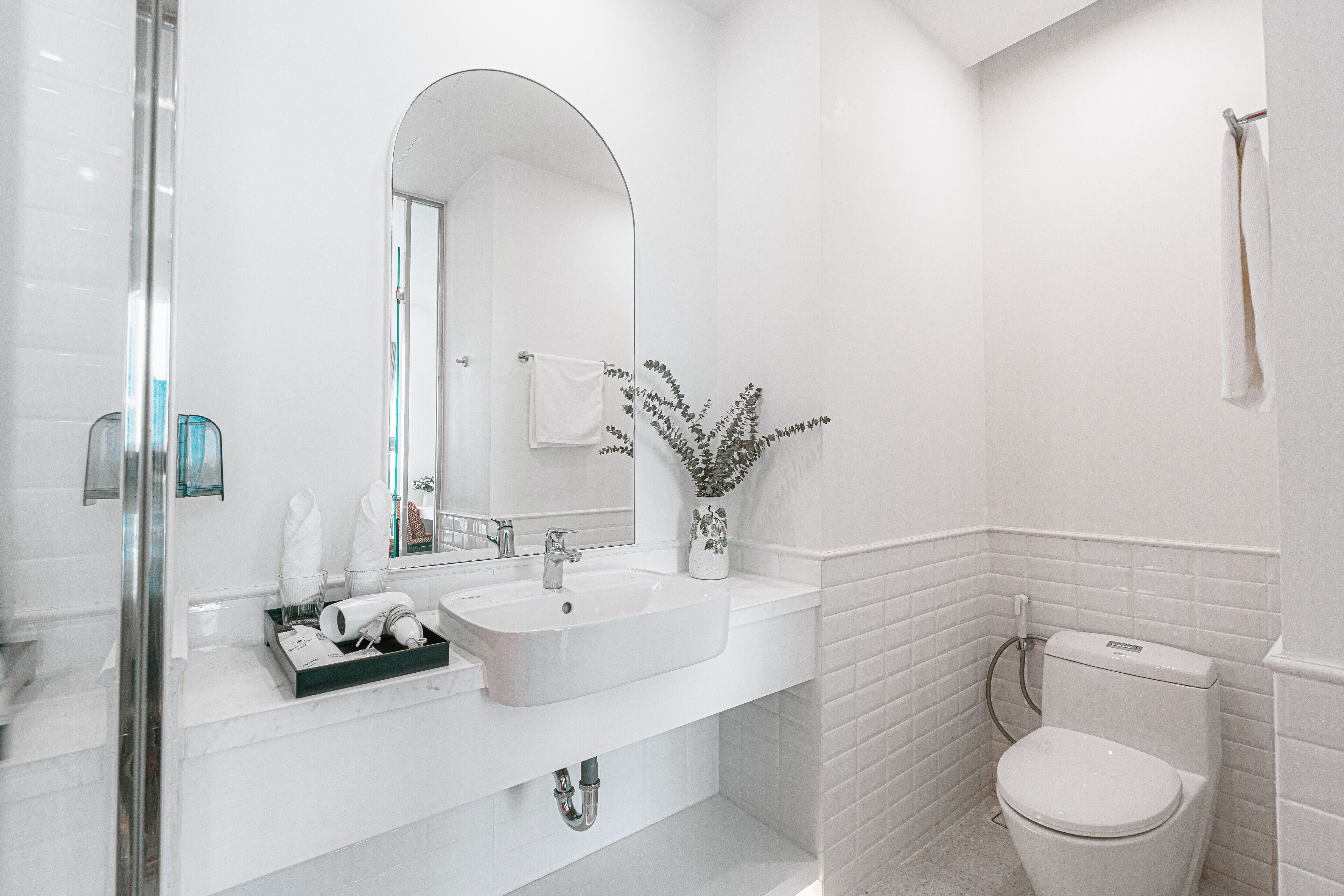 Un baño moderno con lavamanos, espejo y retrete blancos.