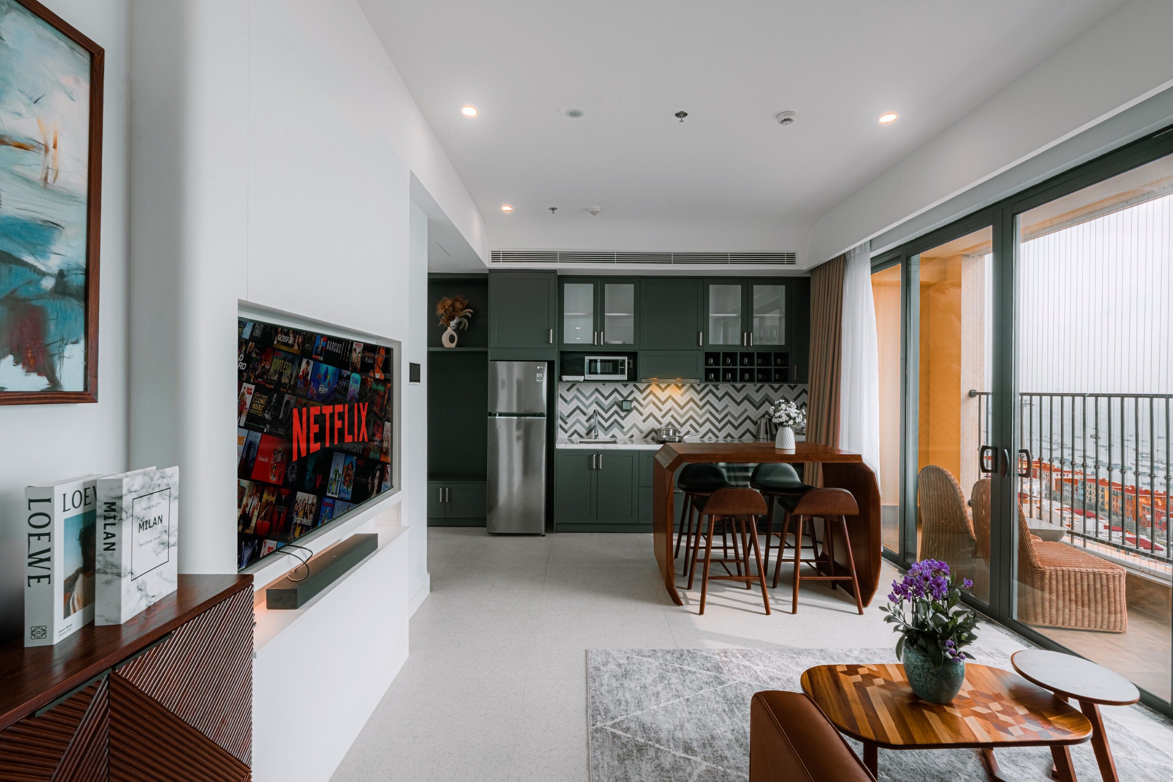 A modern apartment with a kitchen, dining area, and a balcony with a view.