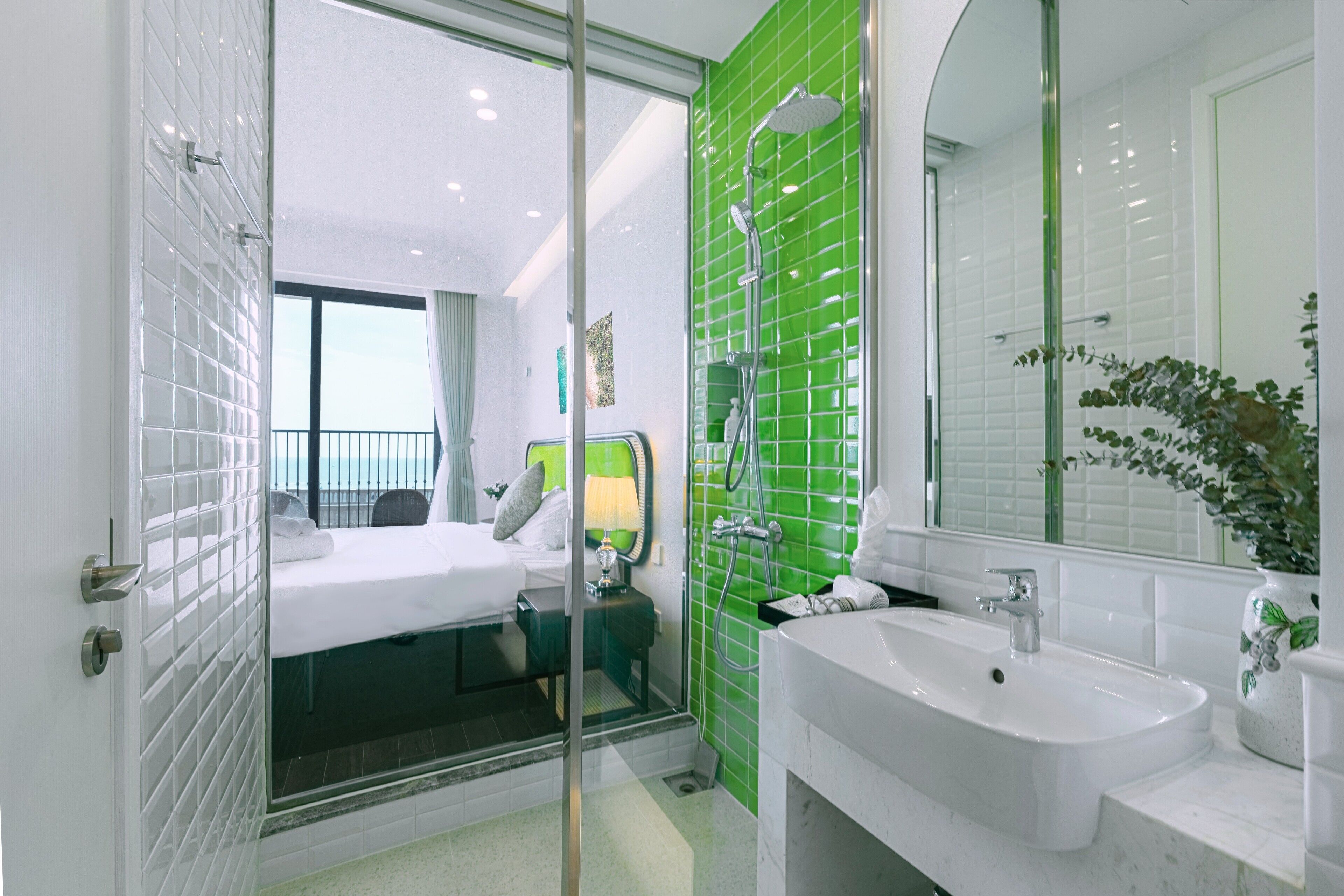 Un baño de hotel moderno con un espejo grande, un lavabo blanco y una zona de ducha.