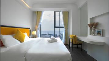 A hotel room with a large bed, a chair, a small table, and a view of the city.