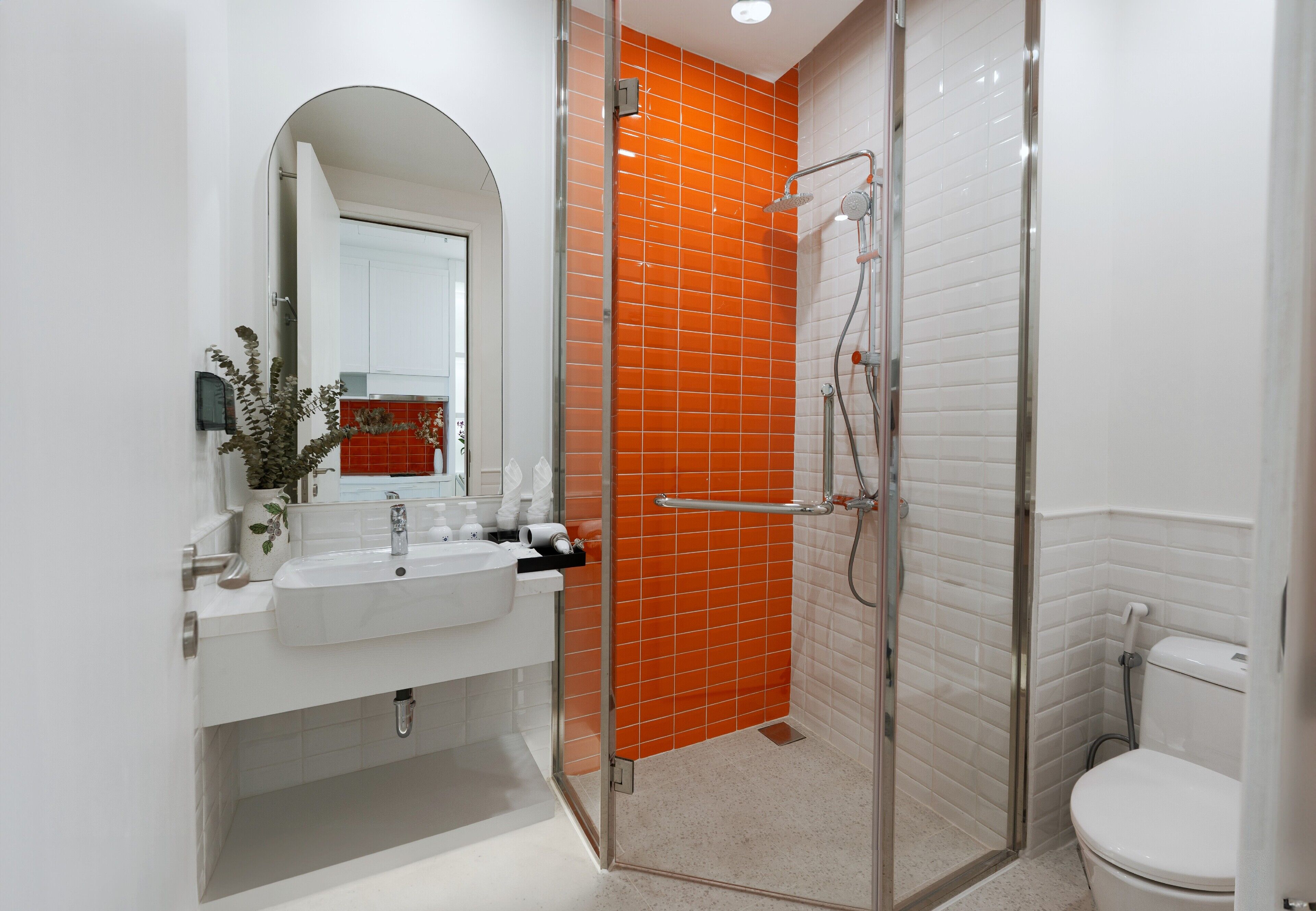 Un baño moderno con cabina de ducha de vidrio, lavabo blanco y un inodoro.