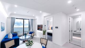 Una habitación de hotel moderna con balcón, una zona de comedor con una mesa redonda y un baño independiente.