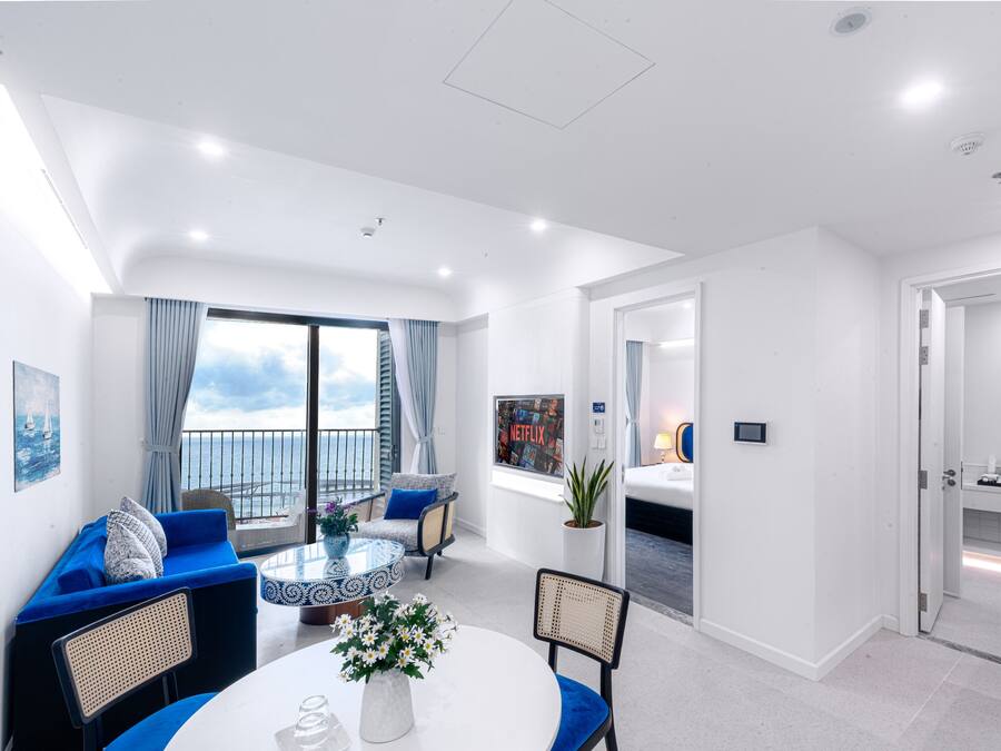 Una habitación de hotel moderna con balcón, una zona de comedor con una mesa redonda y un baño independiente.
